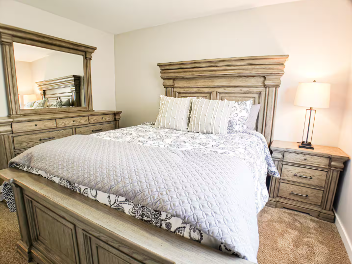King bedroom with rustic wood furniture, dresser with mirror and nightstand