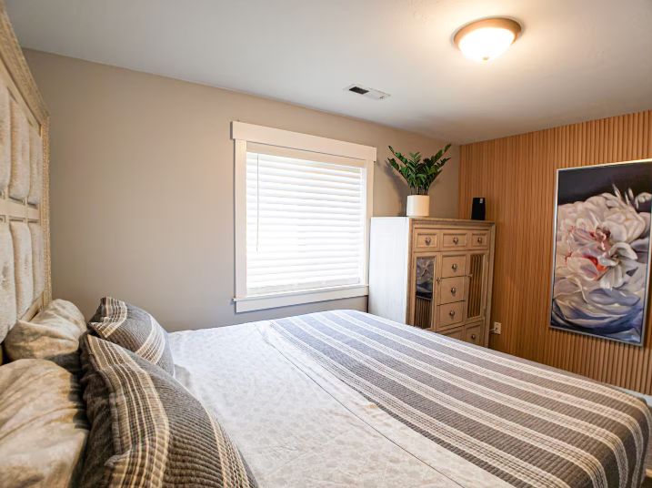 Cozy bedroom with upholstered headboard, wood accent wall and floral artwork