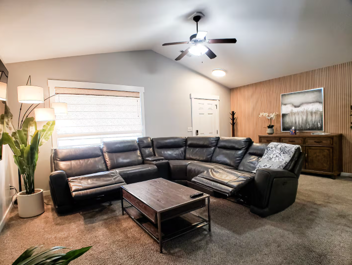 Spacious living room with leather reclining sectional, wood accent wall and vaulted ceiling