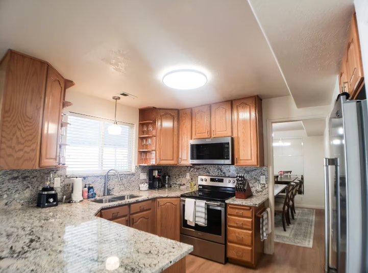Full kitchen with honey oak cabinets, granite countertops, stainless steel appliances and open view to dining area
