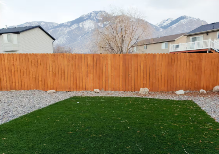 Fully fenced backyard with artificial turf lawn, gravel landscaping, cedar fence and dramatic snow-capped mountain backdrop