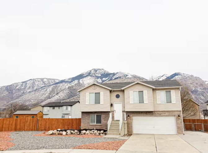 Two-story home with brick accents, 2-car garage, cedar fence and dramatic snow-capped Wasatch Mountain backdrop