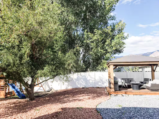 Spacious fenced backyard with mature shade trees, cedar gazebo with seating and mountain views