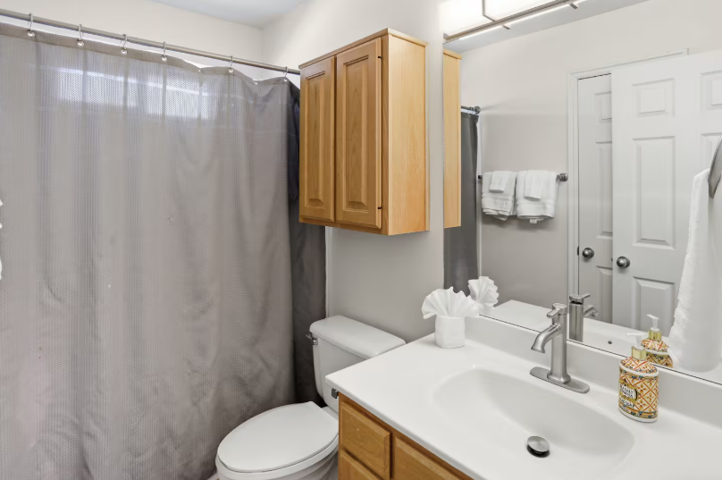 Full bathroom with wood vanity, white countertop, soaking tub, toilet and fresh white towels