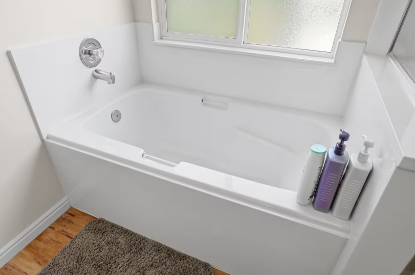Close-up of white soaking tub with chrome fixtures, shampoo and conditioner bottles and frosted window