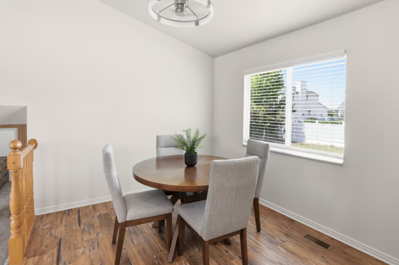 Formal dining room with large wood table seating 6, wood buffet sideboard, abstract artwork and modern ring chandelier